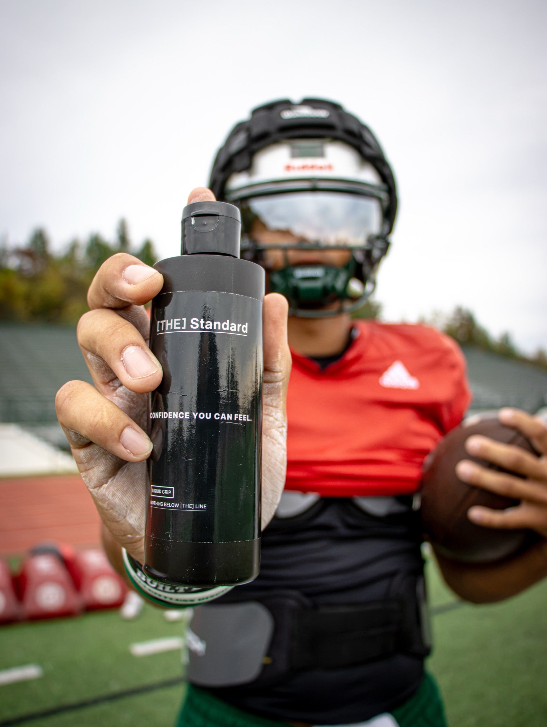 Quarterback holding a bottle of Grip Formula by [THE] Standard
